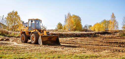 large yellow wheel loader aligns a piece of land for a new building. Preparation of the land for...