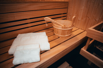 Fototapeta na wymiar Private wooden sauna with folded towels, wooden bucket and a wooden spoon. 