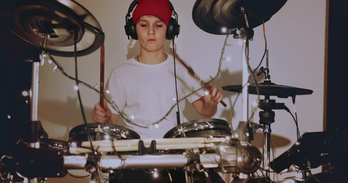 Young teenger boy learning play electronic drums music at living room at home. Self distance education at home during quarantine