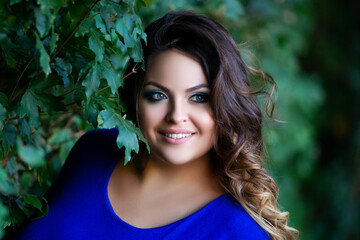 Happy plus size fashion model in blue dress outdoors, fat woman with beauty makeup and hairstyle