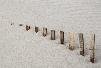 storm fence disappears into drifting beach sand dune