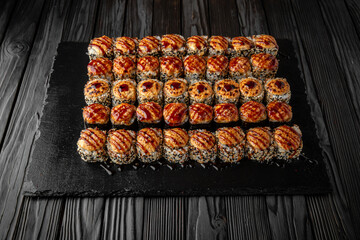 Sushi set with fresh ingredients on black background. Different types of hot fried rolls. Sushi menu. Japanese food. 