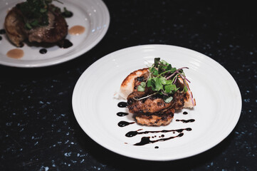 Two dishes of foie gras on a black table