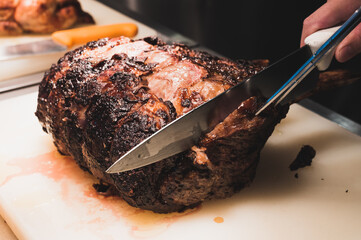 Chef is cutting a big chunk of beef on a white cutting board