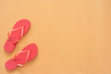 Red flip flops on sandy background with copy space.
