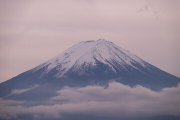 The close up of Mount Fuji in the evening. The top covered by snow and the cloud below it.
