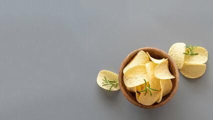 Potato chips in wooden bowl on grey background. Top view.