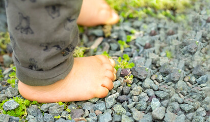 砂利の上に裸足で立つ赤ちゃんの足
