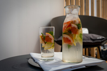 Glass and a vase full of  chilled fresh water and fruit. watermelon, grape, mint and lime
