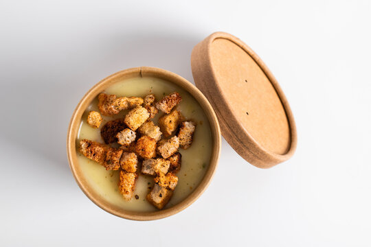 Potato cream soup with croutons in craft containers on a white background. Vegetable soup to go, food delivery