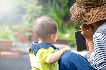 お庭でスマホを見ているおばあちゃんと孫の男の子