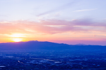 山に沈む夕焼けと河と平野
