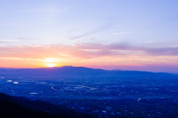 山に沈む夕焼けと河と平野