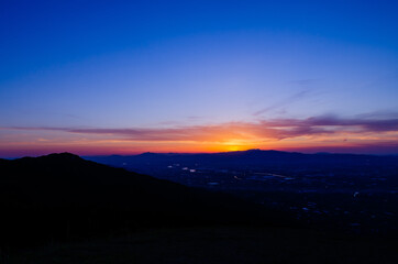 山に沈む夕焼けと河と平野