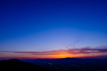 山に沈む夕焼けと河と平野
