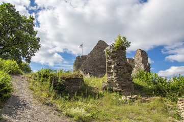Path to the ruins of a medieval castle, illuminated by the sun on a slightly cloudy summer day.