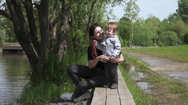 Boy with mom sit on a wooden pier
