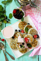 Summer breakfast. Homemade cottage cheese pancakes with poppy seeds, sour cream sauce with strawberries. Top view flat lay background.