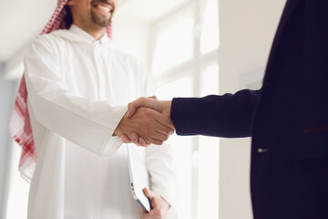 Handshake of arabic and european businesspeople in office.