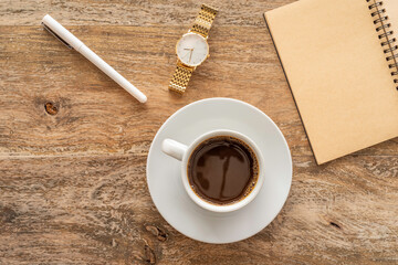 Coffee break. Coffee cup, blank notebook paper, pen, watch on wooden table. Top view.