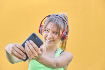 Naklejka premium The pretty girl who listens to smatphone music makes a selfie