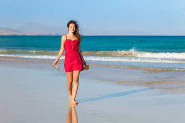 Fototapeta na wymiar Attractive young woman in red dress enjoying the ocean beach