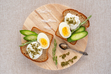 Top view of sandwich made of healthy bread, boiled egg, fresh cucumber, cream cheese with copy space.