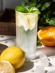 Fresh Summer Homemade citrus lemonade with lemon, mint and ice in glass on a white table.