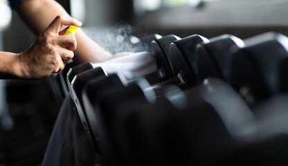 Fitness staff cleaning exercise machines alcohol sanitizer spray at the gym. preventive disease of...