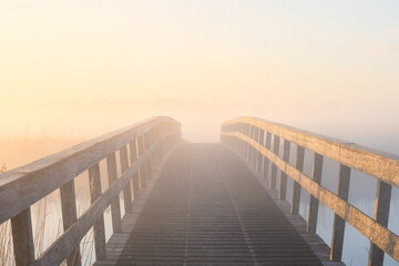 Fototapeta na wymiar wooden bridge in dense fog at sunrise