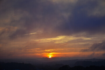 Orange sunset in evening sky with mountain shadows