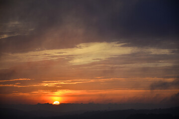 Orange sunset in evening sky with mountain shadows