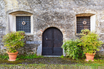 Fototapeta na wymiar Porta d'ingresso e finestre sbarrate in antico edificio di costruzione medievale. Strassoldo, udine, Friuli, italia.