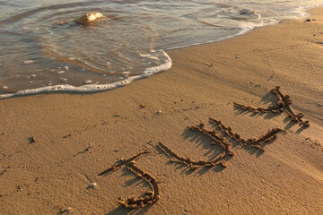 July Hand Written on Sandy Texture at a Sunny Beach with Pebbles with Sea Water in the Background. Travel in the Summer Months Tourism Wallpaper Image. Seascape Vacation Concept.