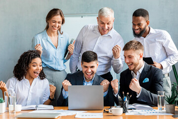 Joyful Coworkers At Laptop Celebrating Successful Deal Sitting In Office