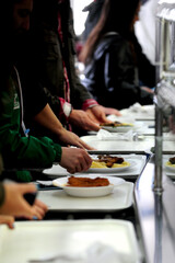 Obraz na płótnie Canvas People waiting in line with food trays 