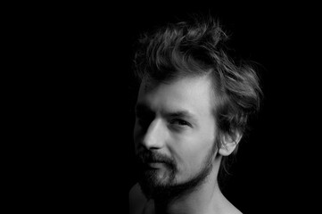 portrait of a guy with a beard and tousled hair on a black background