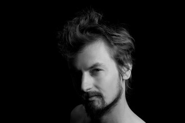 portrait of a guy with a beard and tousled hair on a black background