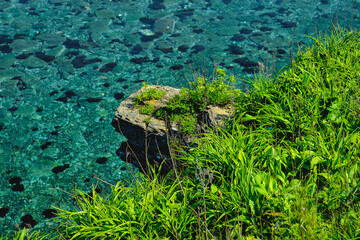 top view to the edge of a steep cliff with turquoise sea background on a summer day at sunrise . Nature and outdoor concept.