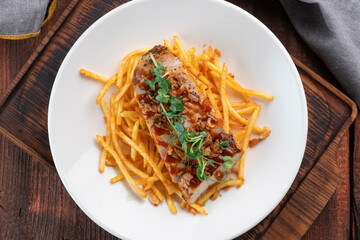 Chicken fillet cut into pieces with French fries on a white plate, a dish for lunch, top view