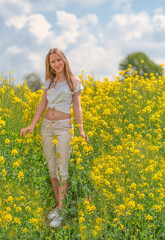 Naklejka na ściany i meble junges kaukasisches Mädchen posiert in der Natur im sommerlichen, gelben Rapsfeld 