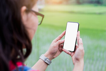 Selective focus young woman using smartphone blurred nature background.