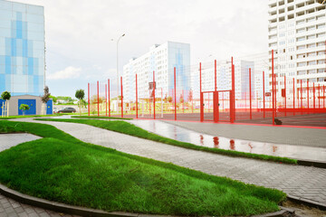 Fototapeta na wymiar Soccer football and basketball field near the building of an apartment building. Empty playground for sports. Green flower beds and walkways.