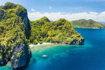 Plakat Aerial drone view of tropical beach with lonely boat on Entalula Island. Karst limestone formation mountain surrounded by blue ocean and beautiful coral reef