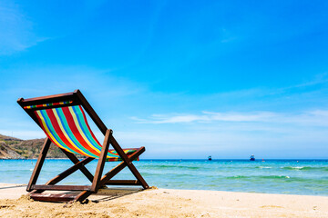 One deck chair on a sandy tropical beach with clear sea, bruise color of water and blue sky on the background