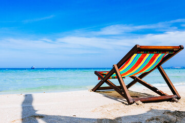 Beach chairs on a sandy beach by the ocean, the concept of relaxation, traveling on a tropical island, relaxation with beautiful views of the bruise sea and blue sky