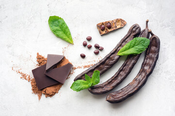 Carob pods on concrete background. Delicious homemade chocolate. Top view. 
