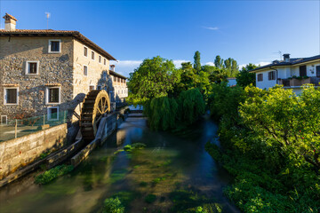 Antico mulino a pale sul fiume nel borgo medievale di Strassoldo. Italia.