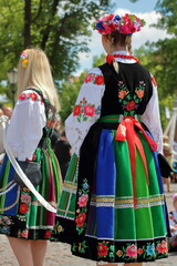 Polish girls in traditional folk costumes from Lowicz region while join Corpus Christi procession in street