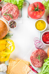 Cooking burger background. Set various cheeseburger  and beefburger ingredients - bun, tomatoes, onion, lettuce, sauces, cheese and raw burger cutlets, ready for barbecue grill. Burger bbq party fest 